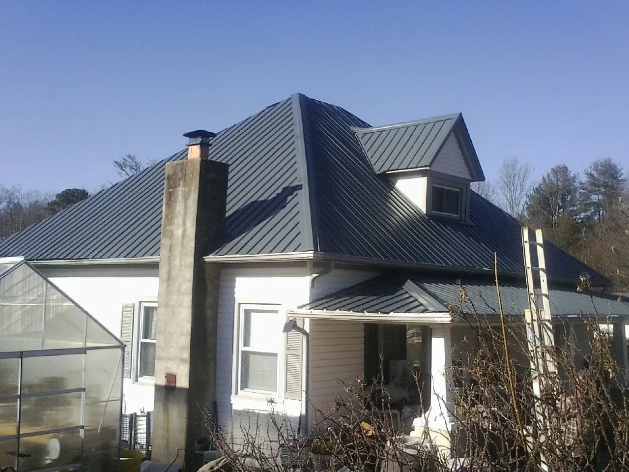 Dark blue standing seam metal roof on a white farmhouse with dormer — Slate & Tile Roof Repair by Roofing Brothers in Salyer