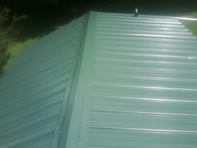 New green metal panels meeting at the ridge of a roof — Flat Roof Repair work by our crew in Salyer