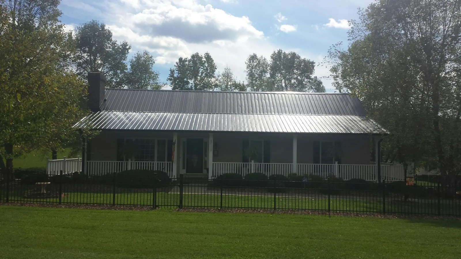 Gray metal roof on a brick ranch with a full width front porch — Gutter Guard Installation work by our crew in Salyer